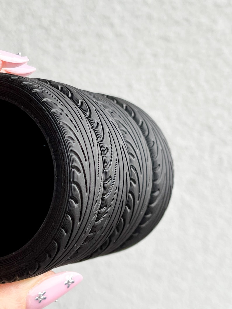 May include: Close-up of three black tire-tread patterned silicone rings stacked on top of each other.
