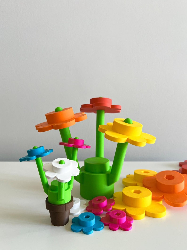 K&ouml;nnte beinhalten: Ein farbenfrohes Spielzeug-Blumengarten-Set mit einer gr&uuml;nen Basis und mehreren Blumenelementen in verschiedenen Farben, darunter Rot, Orange, Gelb, Blau, Wei&szlig; und Rosa.