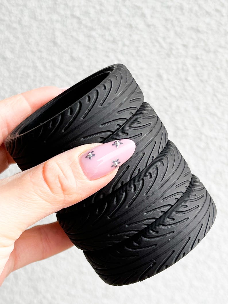 May include: A black foam roller with a tire tread pattern. The roller is made of multiple sections that can be stacked together.