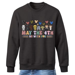 Pode incluir: Uma camisa de frio preta com um gr&aacute;fico de personagens de Star Wars e Mickey Mouse. O texto "May the 4th Be With You" &eacute; impresso abaixo do gr&aacute;fico.