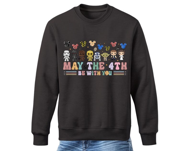 Pode incluir: Uma camisa de frio preta com um gr&aacute;fico de personagens de Star Wars e Mickey Mouse. O texto "May the 4th Be With You" &eacute; impresso abaixo do gr&aacute;fico.
