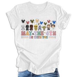 Pode incluir: Camiseta branca com um gr&aacute;fico de personagens de Star Wars segurando bal&otilde;es que dizem "Que a for&ccedil;a esteja com voc&ecirc;".