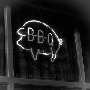 May include: A black and white photo of a neon sign in the shape of a pig with the word "B-B-Q" inside. The sign is hanging in a window with a plaid curtain behind it.