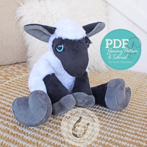 May include: A PDF sewing pattern and tutorial for making a plush toy lamb. The lamb is sitting on a woven rug and has a black face, white fleece, and grey feet. The pattern is by The Rustic Horseshoe.