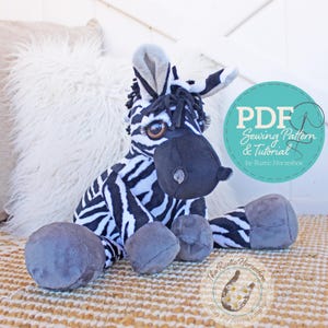 May include: A plush zebra toy with black and white stripes, gray hooves, and a black muzzle. The toy is sitting on a woven rug. A teal circle graphic with the text "PDF Sewing Pattern & Tutorial" is in the background.