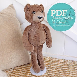 May include: A brown plush teddy bear with a black nose and brown eyes. The bear is standing on a white platform. The image includes the text "PDF Sewing Pattern & Tutorial by Rustic Horseshoe".