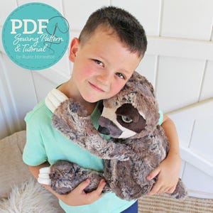 May include: A plush sloth toy with brown and grey faux fur, dark eye patches, and white claws. A circular teal graphic in the corner displays the text PDF Sewing Pattern & Tutorial by Rustic Horseshoe in white lettering.