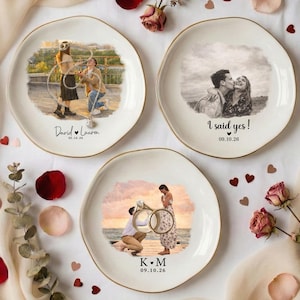 Puede incluir: Tres platos decorativos de cer&aacute;mica con bordes dorados, cada uno con una imagen personalizada de una pareja. Un plato dice "I said yes!" con una fecha. Los otros platos tienen nombres y fechas. Los platos est&aacute;n rodeados de p&eacute;talos de rosa y flores.