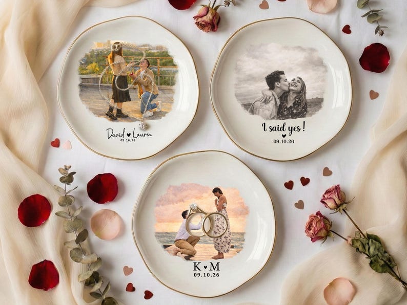 Puede incluir: Tres platos decorativos de cer&aacute;mica con bordes dorados, cada uno con una imagen personalizada de una pareja. Un plato dice "I said yes!" con una fecha. Los otros platos tienen nombres y fechas. Los platos est&aacute;n rodeados de p&eacute;talos de rosa y flores.
