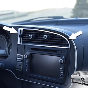 Könnte beinhalten: Das Armaturenbrett eines Autos mit silbernen Zierleisten um die Lüftungsschlitze und das Infotainmentsystem. Das Armaturenbrett ist schwarz, mit einem silbernen Rand. Der Innenraum des Autos verfügt außerdem über einen Tachometer und andere Bedienelemente.