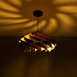 May include: A modern, wooden, spiral-shaped pendant light fixture with a warm, yellow glow.