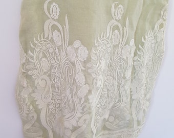May include: A light green sheer tunic with white embroidered floral designs. The embroidery is intricate and covers the entire bottom half of the tunic.