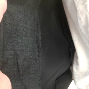 May include: Close-up of the inside of a black skirt with a lining. The lining is a smooth, silky fabric.