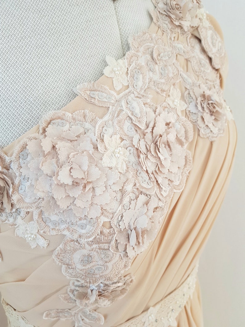 May include: A beige sleeveless dress with a delicate floral lace design. The lace features intricate details and a 3D effect, creating a romantic and elegant look.