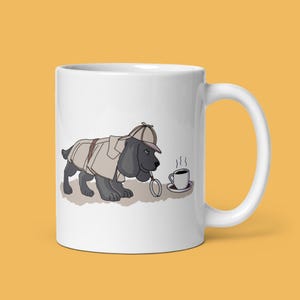 Könnte beinhalten: Weiße Keramiktasse mit einer Cartoon-Illustration eines schwarzen Hundes, der einen Detektivhut trägt und eine Lupe hält. Der Hund schaut auf eine dampfende Tasse Kaffee auf einem Untersetzer.