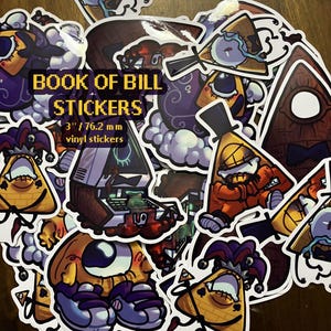 May include: A set of 3 inch (76.2 mm) vinyl stickers featuring various characters from the show "Gravity Falls". The stickers feature Bill Cipher, the character's eye, and a jester version of Bill Cipher. The text "Book of Bill Stickers" is printed on the stickers.