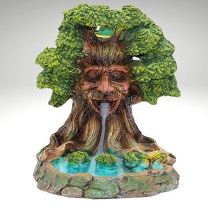 以下が含まれることがあります： 顔と口から流れ落ちる滝のある木の形をしたセラミック製の香炉。香炉のベースは緑の苔のある水たまりです。