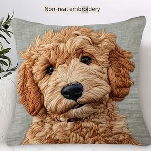 May include: A decorative throw pillow featuring a detailed, embroidered image of a golden doodle dog. The dog has brown fur, a black nose, and dark eyes. The pillow has a gray background and the text "Non-real embroidery".
