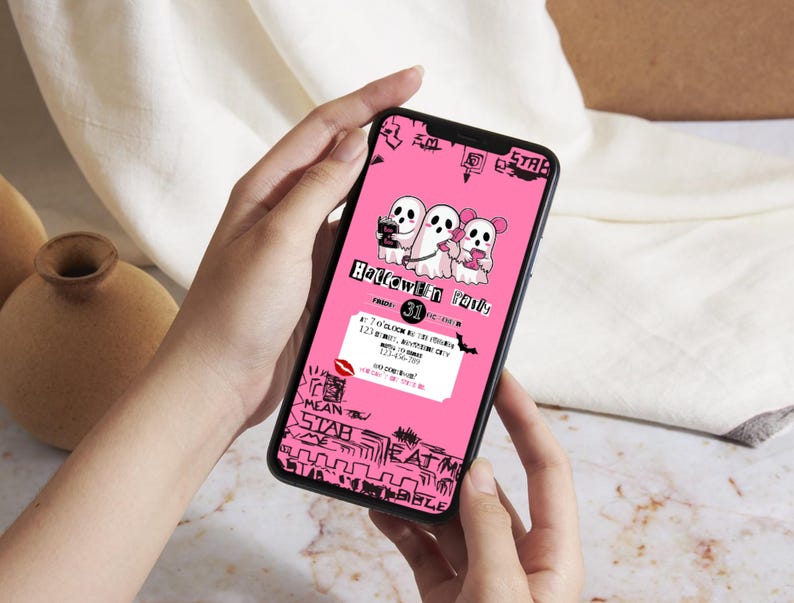 May include: A smartphone displaying a pink Halloween-themed graphic. The graphic features three cartoon ghosts and the text "Halloween Party". Additional text includes event details and decorative elements in black.