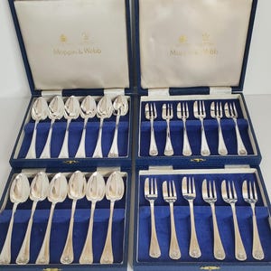May include: Four sets of silver cutlery in blue velvet presentation boxes. Each box contains spoons or forks. The boxes are labelled "Mappin & Webb" in gold lettering. The cutlery has a decorative floral design.