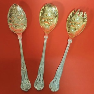 Peut inclure: Trois ustensiles de service ornés avec des manches argentés et des cuillères dorées. Les cuillères présentent un motif détaillé et les manches ont un motif décoratif. L'ensemble comprend une cuillère et une fourchette.