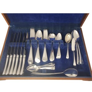 May include: A silver-toned cutlery set presented in a wooden storage box with a blue velvet lining. The collection comprises various knives, forks, and spoons, all featuring a polished metallic finish and a traditional handle design throughout the set.