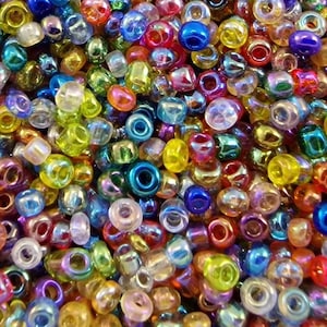 Könnte beinhalten: Nahaufnahme einer Sammlung farbenfroher Glasperlen. Die Perlen haben verschiedene Formen und Größen und eine Vielzahl von Farben, darunter Blau, Grün, Gelb, Orange und Rot. Einige Perlen haben eine glänzende, irisierende Oberfläche.