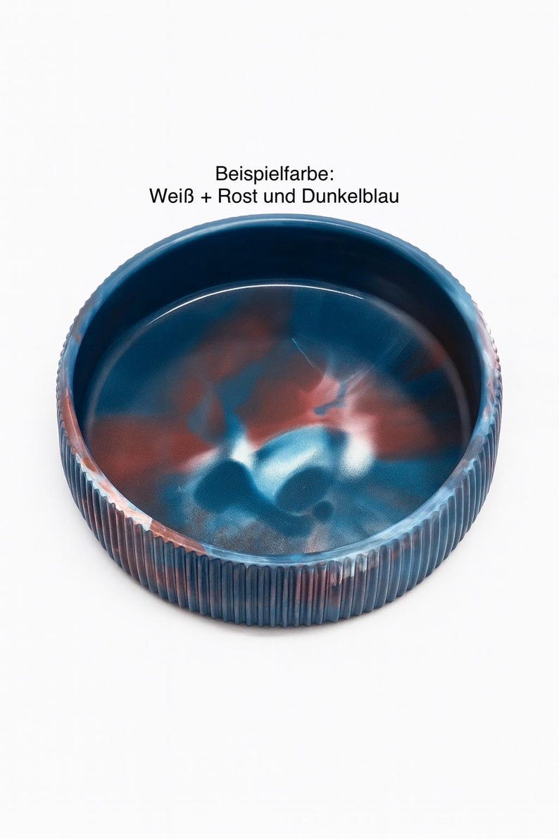 Op de afbeelding: Een ronde, decoratieve kom met een geribbelde buitenkant en een gemarmerd interieur. De binnenkant van de kom heeft een mix van blauwe, rode en witte kleuren. De tekst "Beispielfarbe: Wei&szlig; + Rost und Dunkelblau" is zichtbaar.