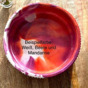 Op de afbeelding: Een ronde, decoratieve kom met een getextureerde rand. De binnenkant heeft een mix van wit, bes en mandarijnkleuren. De tekst "Beispielfarbe: Wei&szlig;, Beere und Mandarine" is zichtbaar op de kom.