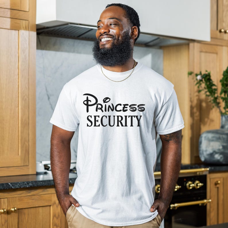 Puede incluir: Una camiseta blanca con un gr&aacute;fico negro que dice "Princess Security" en una fuente estilizada.