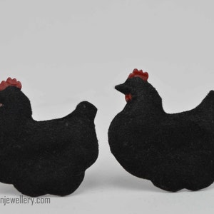 Puede incluir: Un par de pendientes de pollo de fieltro negro con crestas de fieltro rojo.