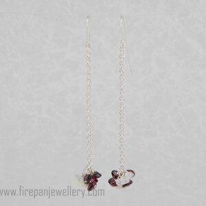 May include: Silver dangle earrings with a cluster of small, faceted, red and white gemstones at the bottom.