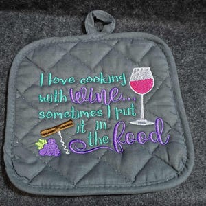 May include: Gray quilted pot holder with embroidered text and wine-themed graphics. The text reads "I love cooking with wine... sometimes I put it in the food." Features a wine glass, corkscrew, and grapes.