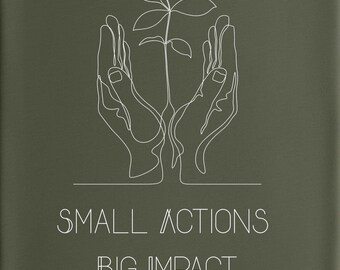 May include: Olive green t-shirt with a crew neck. The shirt features a white line drawing of hands cradling a plant. Below the graphic, the text reads "SMALL ACTIONS BIG IMPACT". The shirt is folded on a woven, circular surface.