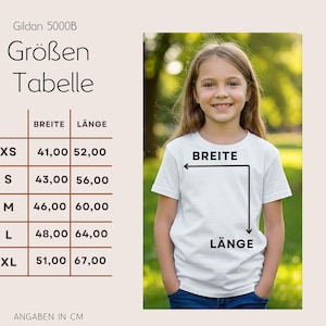 May include: A white Gildan 5000B t-shirt on a young girl, with a size chart in centimeters. The chart shows measurements for XS, S, M, L, and XL sizes, indicating width and length in cm. The text "BREITE" and "L&Auml;NGE" are also visible.