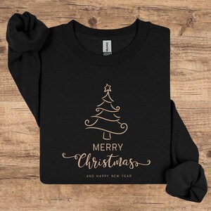 May include: Black sweatshirt with a gold Christmas tree design and the words "MERRY Christmas AND HAPPY NEW YEAR" in a decorative font. The sweatshirt is made of a soft material and is perfect for the holiday season.