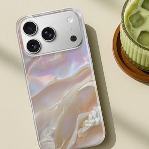 Può includere: Una custodia trasparente per telefono con un design perlato e vorticoso nei toni del bianco, pesca e lavanda. La custodia ha un bordo trasparente e un ritaglio per la fotocamera con tre obiettivi e un flash.