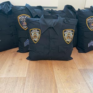 May include: A group of five black pillow covers with embroidered patches that say "Police Department, City of New York" and "Police, Lake Success, NY".