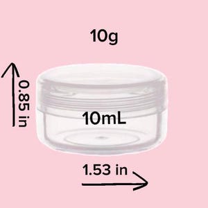May include: A clear, round, empty plastic cosmetic jar with a screw-top lid. The jar is labeled with a capacity of 10g and 10mL. Dimensions indicated are 0.85 inches in height and 1.53 inches in diameter, shown with black arrows and text.