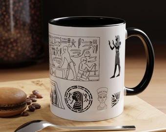 May include: White ceramic mug with a black rim and handle. The mug features a black and white illustration of ancient Egyptian hieroglyphics and figures.