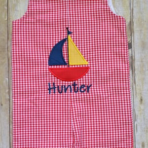 Red gingham short all with a boat appliqué and name embroidered on it.