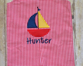 Red gingham short all with a boat appliqué and name embroidered on it.