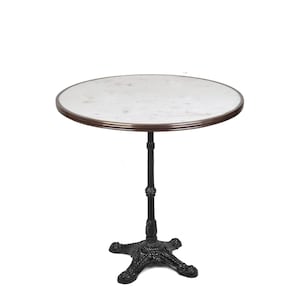 May include: A round white marble table top with a copper trim sits on a black cast iron base with three legs. The table is approximately 30 inches in diameter.