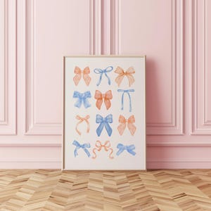 Peut inclure: Une affiche encadr&eacute;e pr&eacute;sentant des illustrations &agrave; l'aquarelle de n&oelig;uds dans des tons orange et bleu. Les n&oelig;uds sont dispos&eacute;s en grille sur un fond blanc. Le cadre est de couleur bois clair, et le fond est un mur rose.