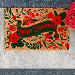 Merry Christmas floral doormat featuring a natural background filled with red blooms, holiday berries and dark green foliage around a central festive greeting. This Christmas welcome mat brings botanical holiday style to the front door and works as seasonal porch decor or a decorative Christmas gift for homeowners.