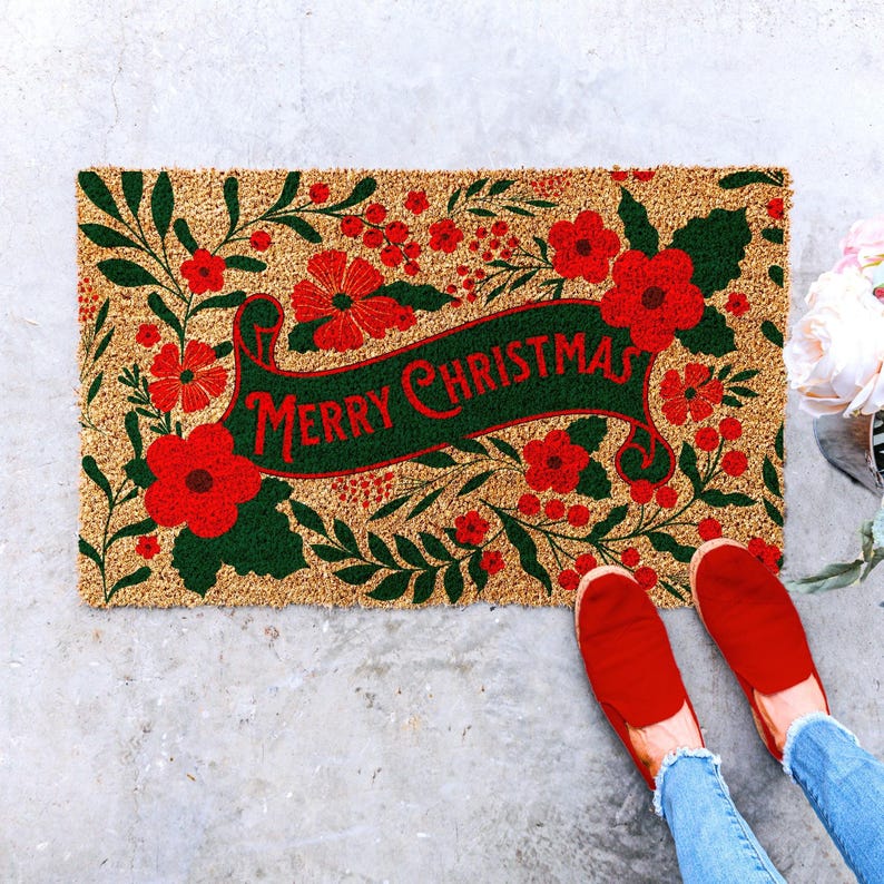 Christmas doormat with a centered Merry Christmas greeting framed by red flowers, berries and deep green foliage. The colorful botanical layout creates a festive holiday welcome mat for the front door and works naturally with red and green Christmas porch decor, seasonal entryway styling and floral holiday decorations.