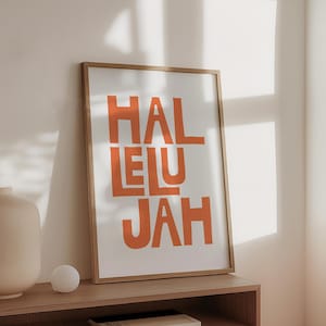 Może przedstawiać: Wydruk w ramie z napisem "Alleluja" w pomarańczowych literach na białym tle.