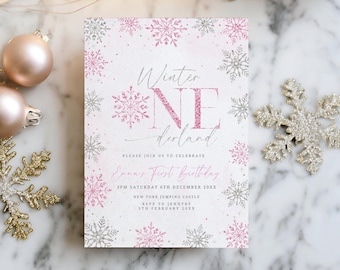 May include: A festive invitation with the text "Winter NE derland" in pink glitter and script font, surrounded by pink and silver snowflakes. The invitation includes details for a first birthday celebration, with decorative Christmas ornaments in the background.