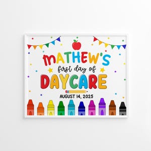 Può includere: Un cartello bianco incorniciato con la scritta "MATHEW'S first day of DAYCARE" in lettere colorate. Il cartello include una mela rossa, stelle e una fila di pastelli. Viene visualizzata anche la data "AUGUST 14, 2025".