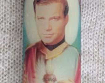 May include: A glass candle with a stained glass design featuring a man with a heart in his chest. The man is wearing a pink robe and has a halo above his head.